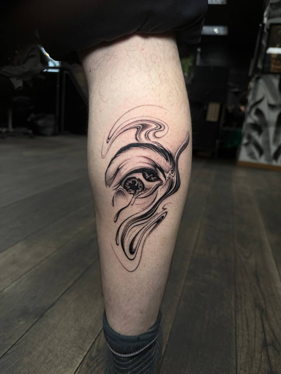 Surreales Concept-Tattoo — Auge mit fließenden Linien an der Wade