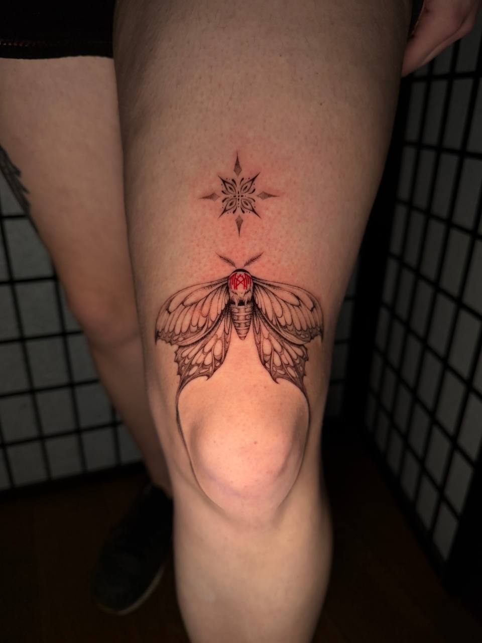Filigranes Fineline Motten-Tattoo mit Stern am Oberschenkel